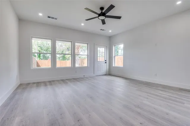 a view of an empty room with a window and wooden floor