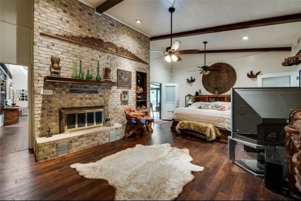 6049 West Red Bird Lane Dallas, TX 75236 - Photo 16 of 34 a bedroom with a bed a fireplace and wooden floor