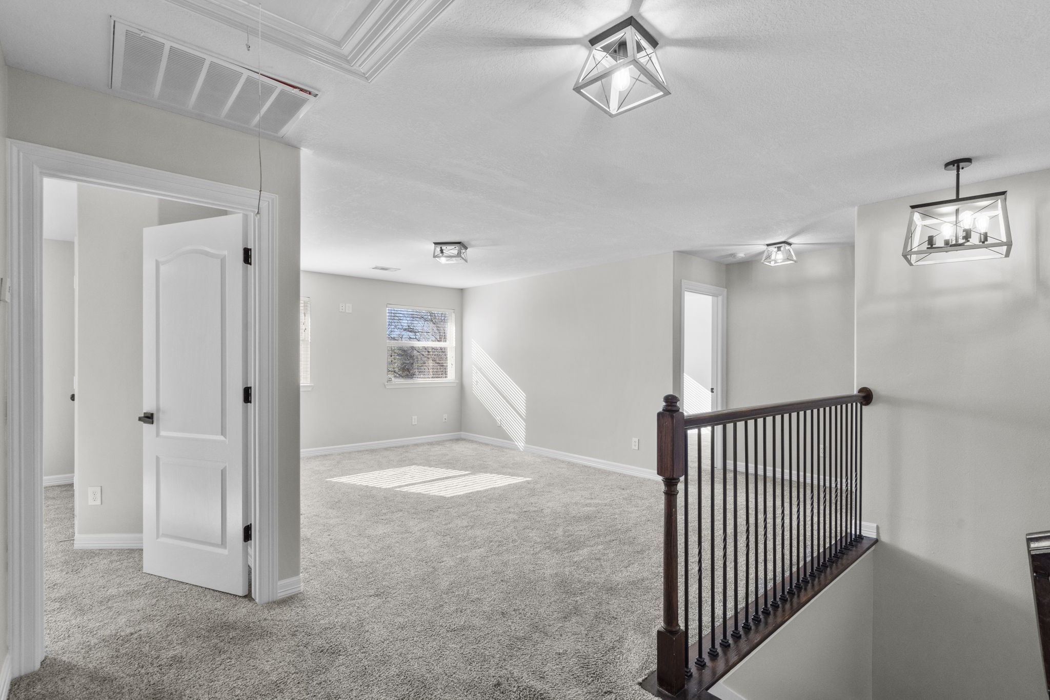 2730 Lawrence Road Kemah, TX 77565 - Photo 29 of 46 Bright and spacious upper hallway with modern light fixtures, plush carpeting, and multiple doorways leading to additional rooms. A dark wood railing borders a staircase, enhancing the open feel.
