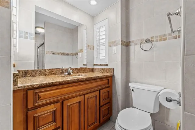 a bathroom with a granite countertop toilet sink and mirror