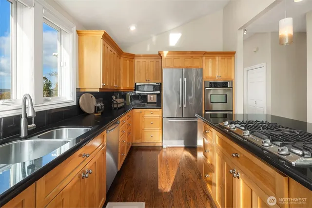 a kitchen with stainless steel appliances granite countertop a sink a stove and a refrigerator