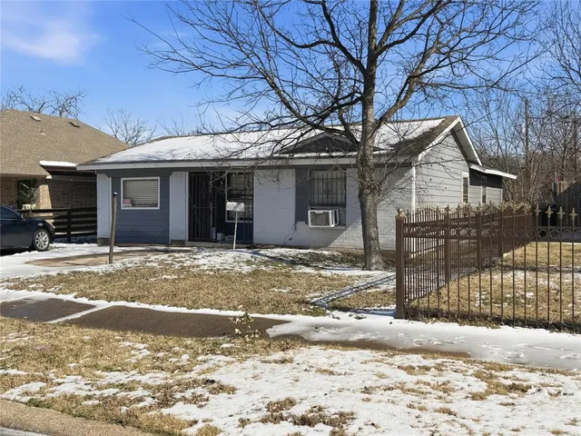 a front view of a house with a dirt yard and a large tree
