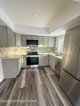 a kitchen with stainless steel appliances granite countertop a stove top oven a sink dishwasher and a refrigerator