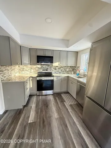 a kitchen with stainless steel appliances granite countertop a stove top oven a sink dishwasher and a refrigerator