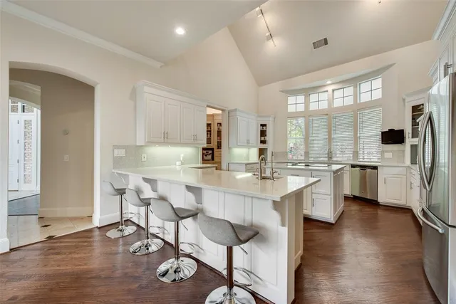 a kitchen with stainless steel appliances a dining table chairs refrigerator and sink
