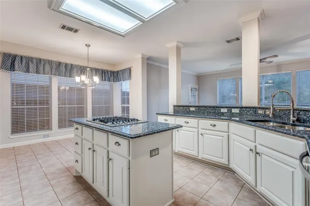 an empty room with chandelier fan and windows