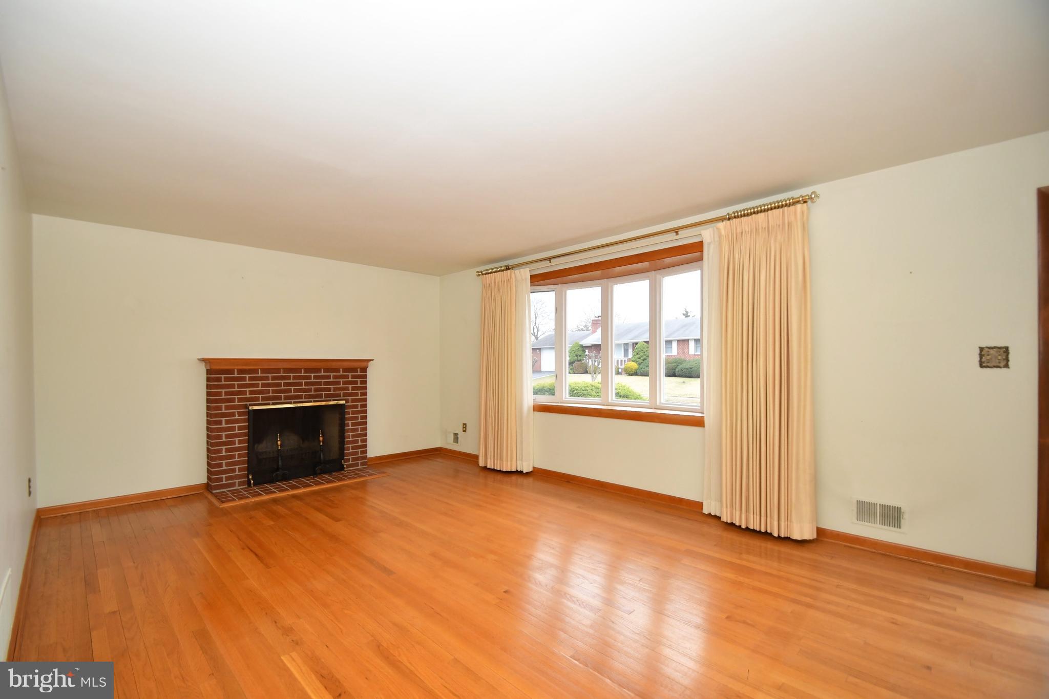 9412 Dawnvale Road Baltimore, MD 21236 - Photo 4 of 28 an empty room with a fireplace and windows
