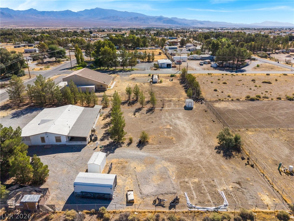 1551 West Wilson Road Pahrump, NV 89048 - Photo 54 of 68 An expansive fenced lot offers functional outbuildings against a backdrop of distant mountain ranges.