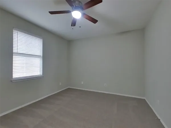 an empty room with a window and a fan