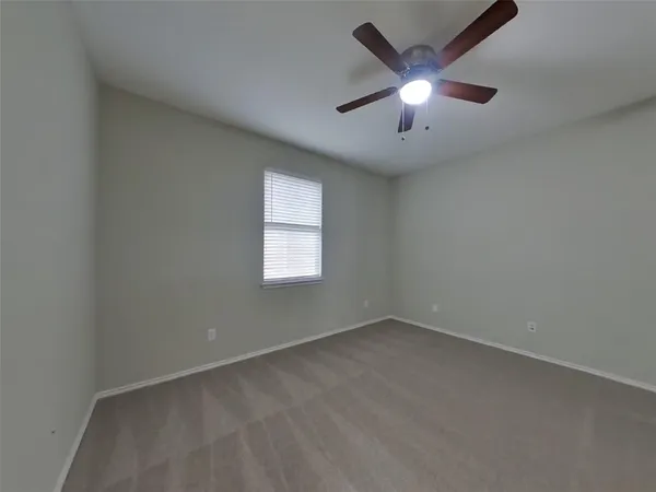 an empty room with ceiling fan and window