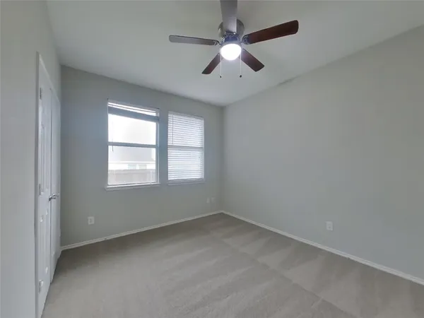 an empty room with a window and a fan