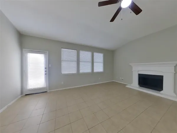an empty room with chandelier fan and windows