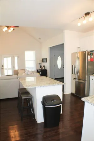 a kitchen with stainless steel appliances granite countertop a refrigerator a sink a stove and island with wooden floor