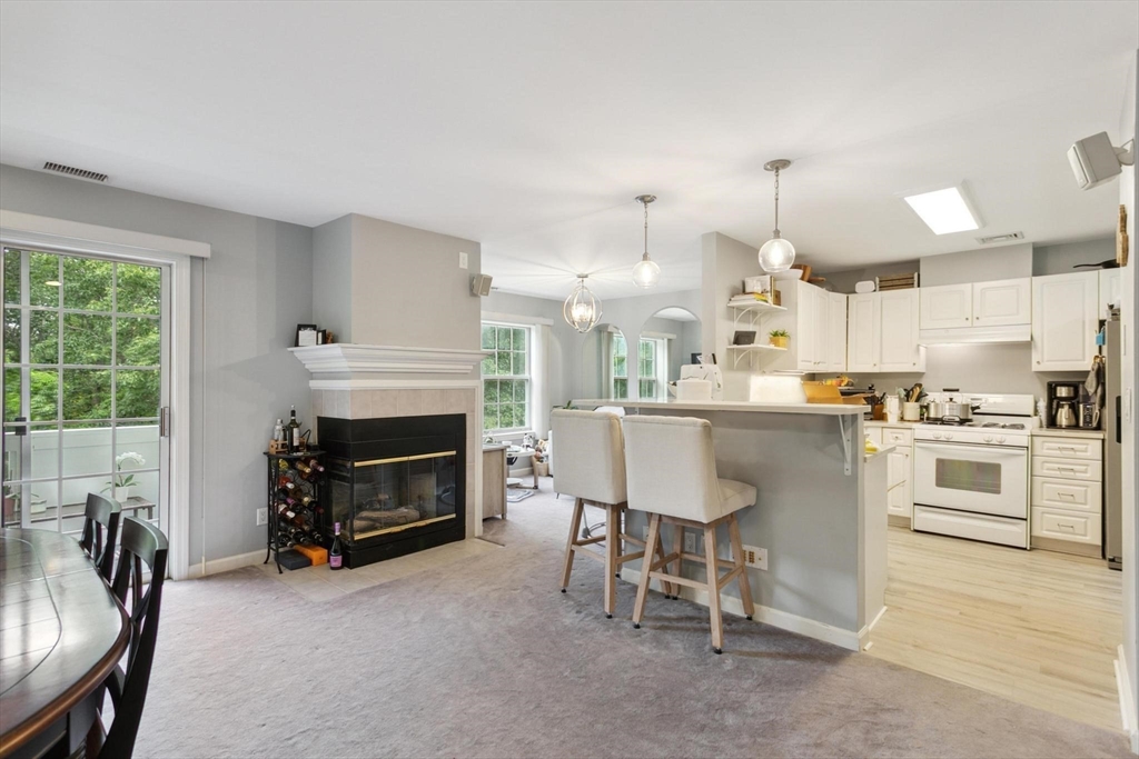 707 Gazebo Circle, Unit 707 Reading, MA 01867 - Photo 3 of 41 a living room with furniture a fireplace and kitchen view
