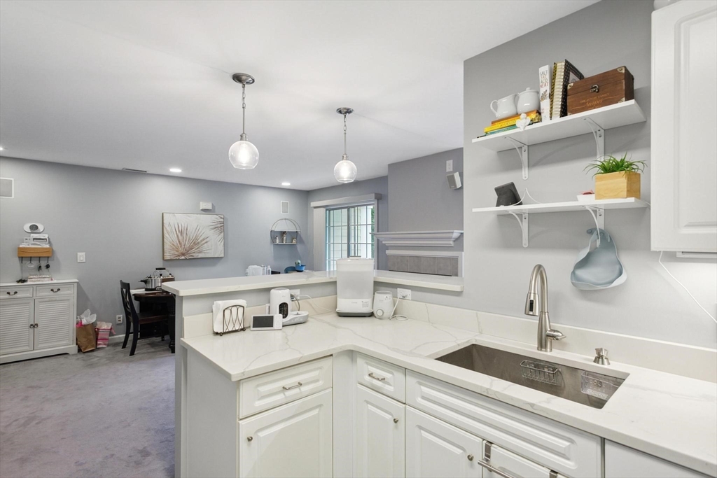 707 Gazebo Circle, Unit 707 Reading, MA 01867 - Photo 9 of 41 a kitchen with a sink dishwasher and white cabinets with wooden floor