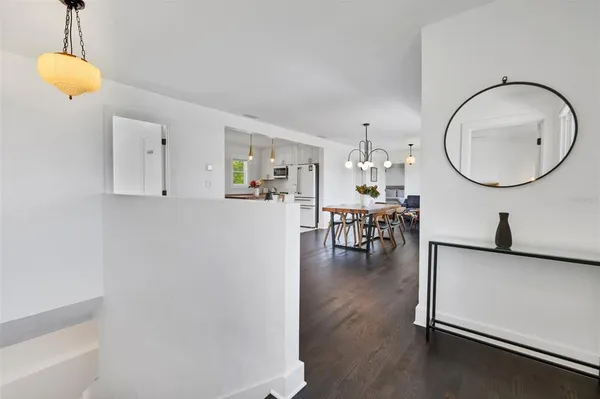 a kitchen with kitchen island granite countertop a stove a sink a microwave a dining table and chairs with wooden floor
