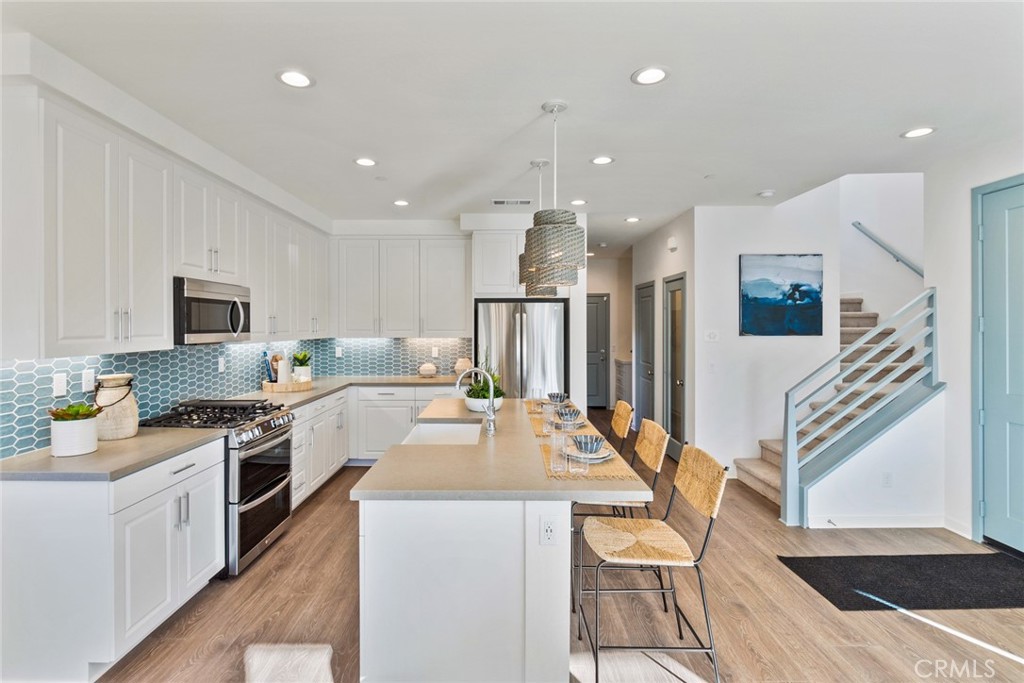 12352 Van Gogh Place Yucaipa, CA 92399 - Photo 23 of 44 a kitchen with stainless steel appliances granite countertop a refrigerator a stove top oven a sink dishwasher and white cabinets with wooden floor