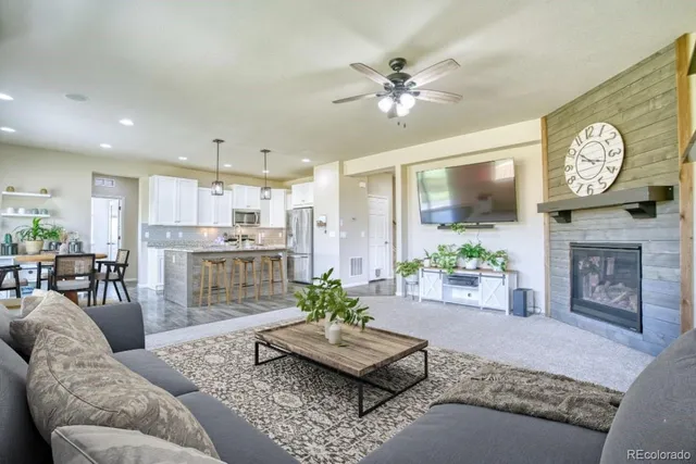 a living room with furniture a fireplace a rug and a large window