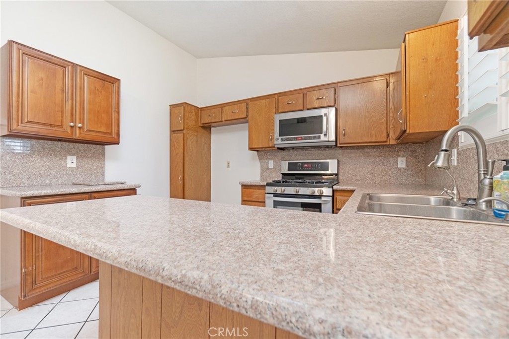 7210 Mesada Street Rancho Cucamonga, CA 91701 - Photo 15 of 32 a kitchen with stainless steel appliances a sink a stove a microwave a sink and cabinets