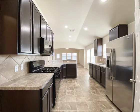 a kitchen with stainless steel appliances granite countertop a refrigerator a stove and a sink