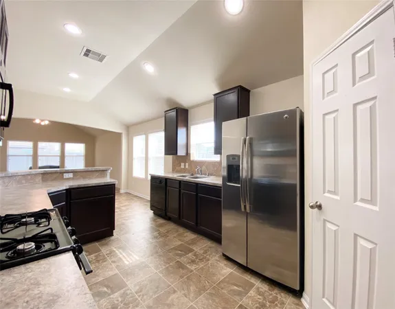 a kitchen with stainless steel appliances granite countertop a refrigerator and a stove