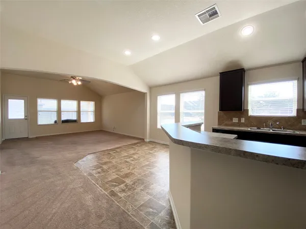 a view of an empty room with a window and a kitchen