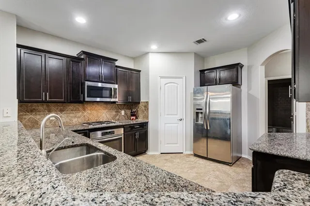 a kitchen with granite countertop a refrigerator and a sink