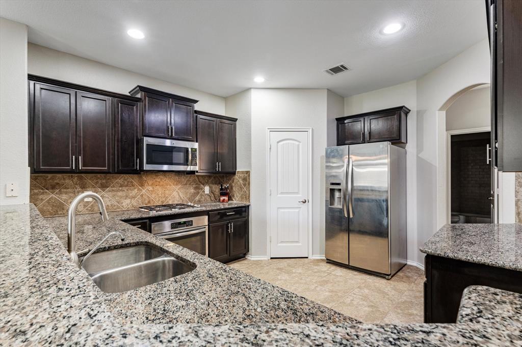 a kitchen with granite countertop a refrigerator and a sink