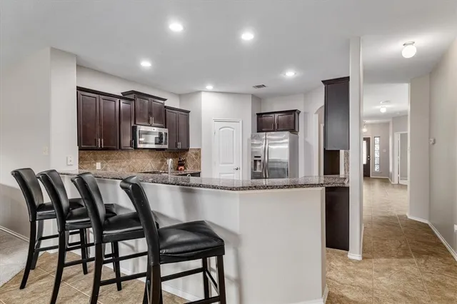 a kitchen with granite countertop a table chairs microwave and cabinets
