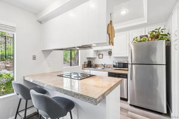 a kitchen with granite countertop a table chairs stove and refrigerator