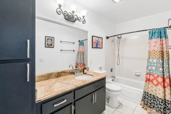 a bathroom with a granite countertop sink a toilet and shower