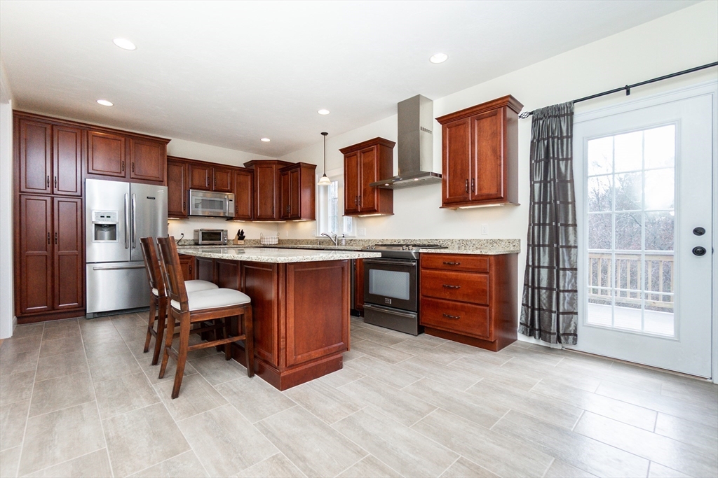 31 Whitehall Way Bellingham, MA 02019 - Photo 4 of 39 a kitchen with stainless steel appliances kitchen island granite countertop a table chairs sink and refrigerator