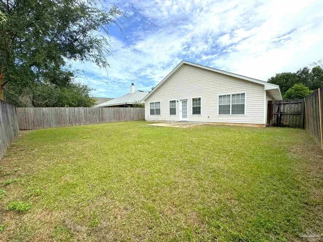 a view of a house with a yard and a large tree