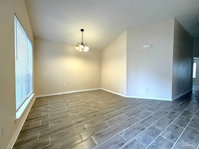 a view of an empty room with window and chandelier fan