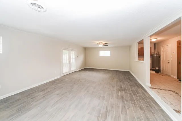 an empty room with wooden floor and windows