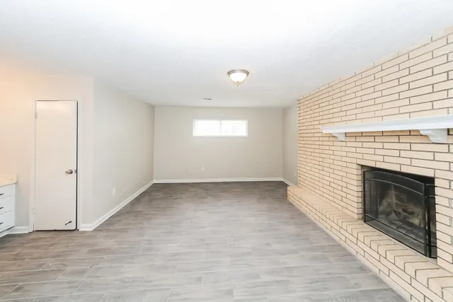 an empty room with windows and fireplace