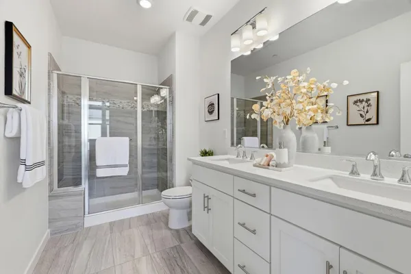 a bathroom with a double vanity sink toilet and shower