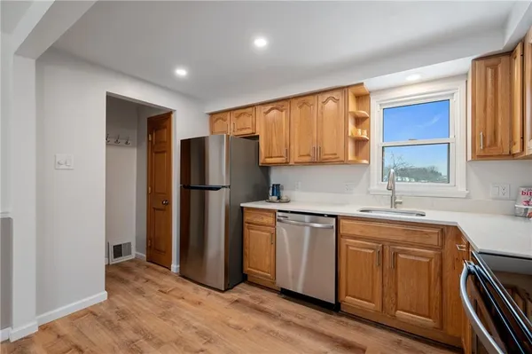 a kitchen with stainless steel appliances granite countertop a refrigerator a sink dishwasher and wooden cabinets with wooden floor