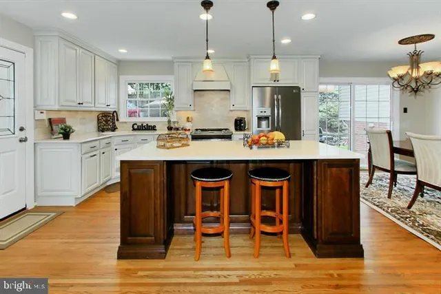 a kitchen with stainless steel appliances granite countertop a stove a refrigerator a sink dishwasher and a dining table with wooden floor