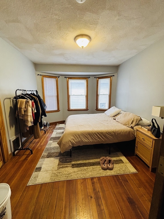 24 Meacham Street, Unit 2 Somerville, MA 02145 - Photo 3 of 11 a bedroom with a bed and wooden floor