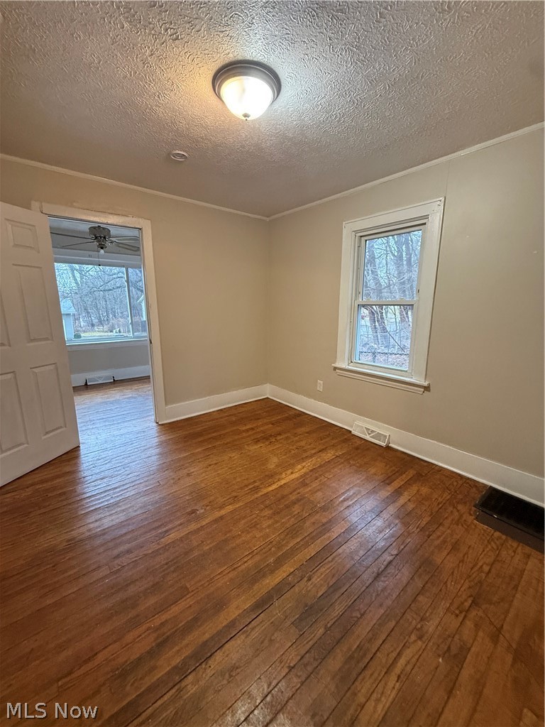 805 Carpenter Street Akron, OH 44310 - Photo 7 of 8 Unfurnished room featuring dark wood-style floors, a textured ceiling, plenty of natural light, and ornamental molding