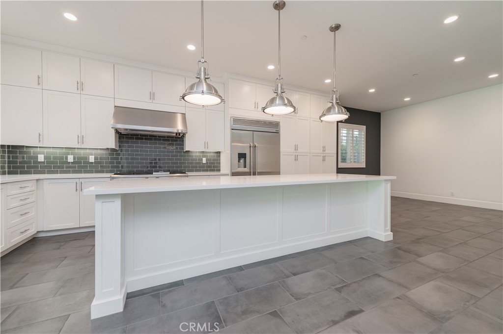91 Rockinghorse Irvine, CA 92602 - Photo 11 of 48 a large kitchen with kitchen island granite countertop a stove a sink a island and a white cabinets