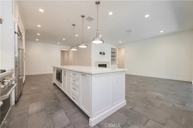a large white kitchen with a large island oven a stove and a refrigerator with wooden floor
