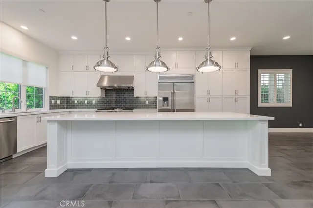 a large kitchen with kitchen island a large counter top a sink and a window