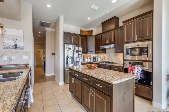 a kitchen with stainless steel appliances granite countertop a stove refrigerator and a sink