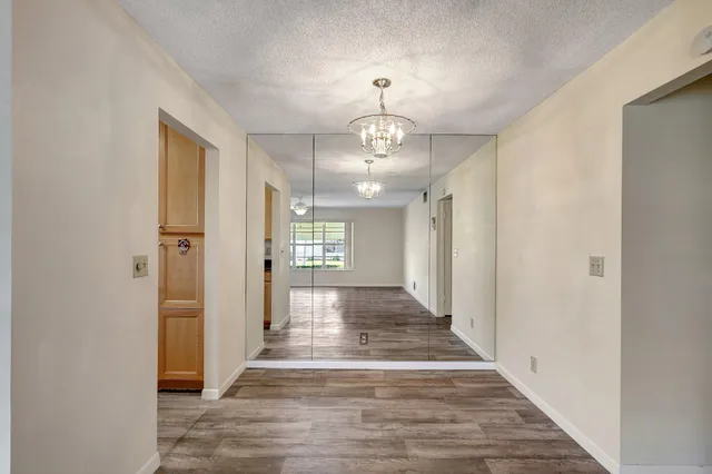 a view of a hallway with wooden floor and chandelier