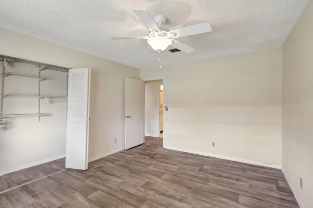 an empty room with wooden floor and fan