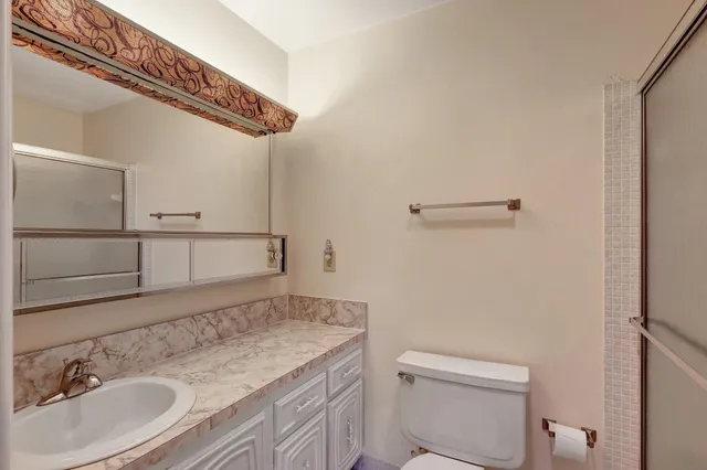 a bathroom with a granite countertop sink a toilet and a mirror
