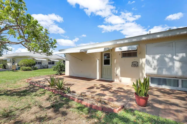a front view of a house with a yard and potted plants