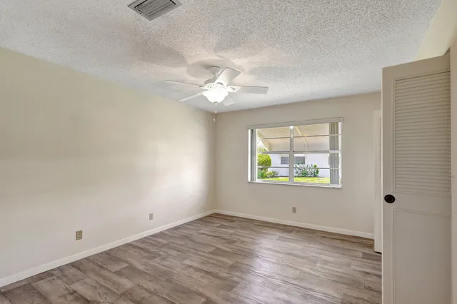 an empty room with a window and a ceiling fan